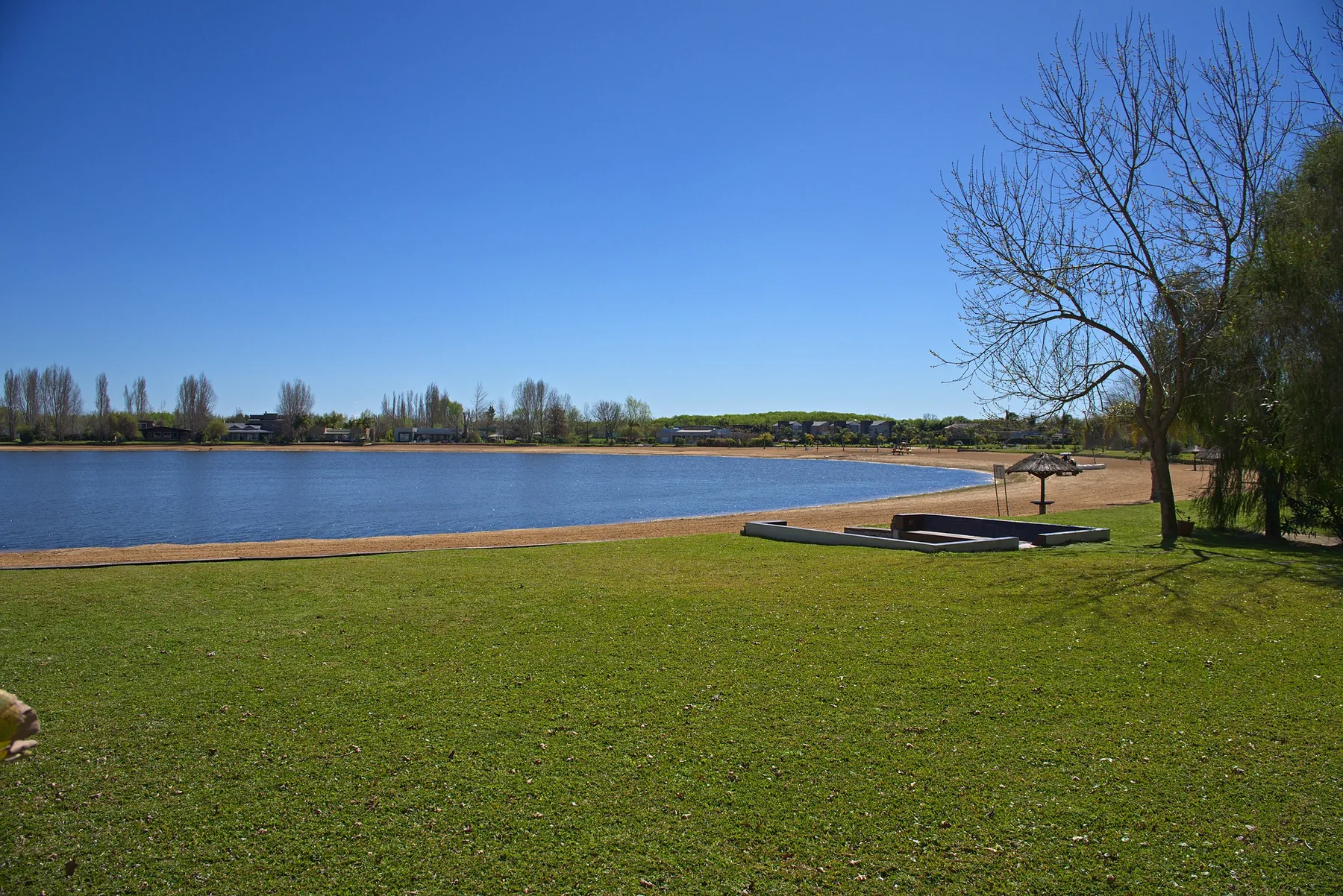 El parque baja sin interrupción hasta la playa de arena de la laguna.